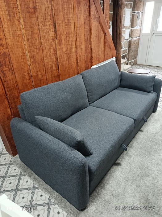 Um sofá cama, três Tvs e um refrigerador.