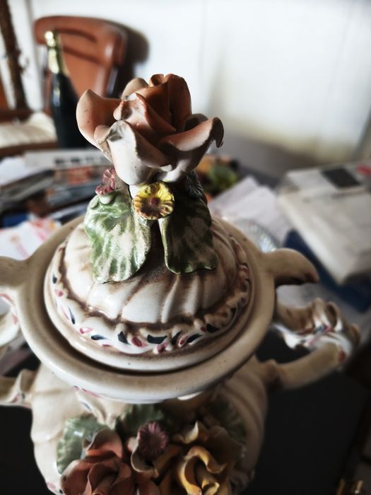 peça cerâmica decorativa ou uma peça de porcelana. Tem a forma de um vaso ou urna com duas pegas, com uma tampa separada