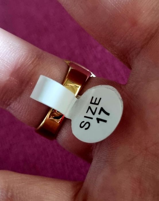 Anel dourado, em aço, com grande pedra de vidro transparente oval. T17