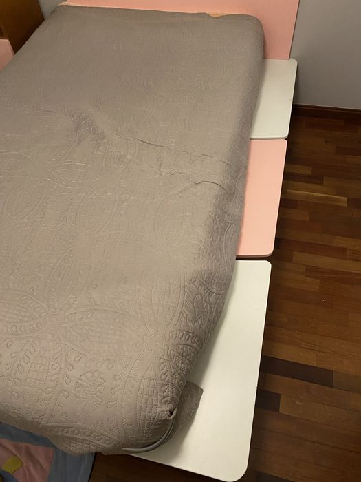 Cama em tons rosa e branco com suporte lateral