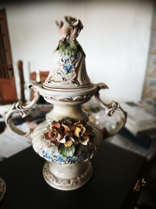 peça cerâmica decorativa ou uma peça de porcelana. Tem a forma de um vaso ou urna com duas pegas, com uma tampa separada