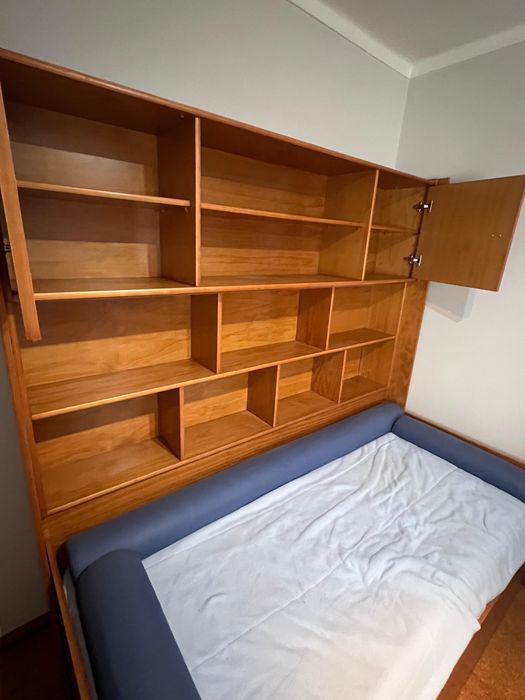 Cama individual com móvel associado com gaveta e colchão.