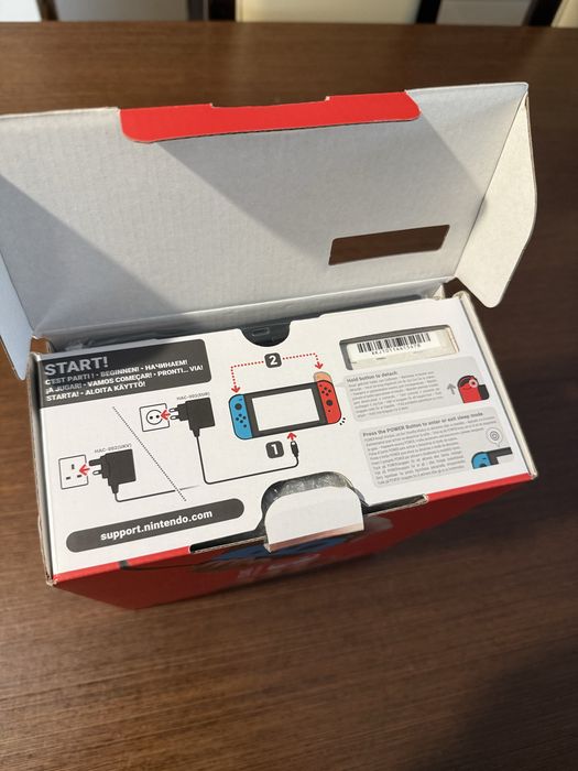 Vendo Nintendo Switch clássica com comandos Joy-Con azul e vermelho, em estado novo.