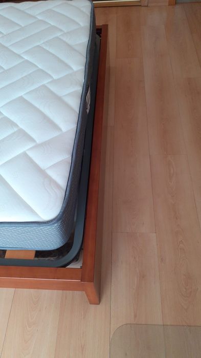 Cama de casal com uma mesa de cabeceira e colchão incluído