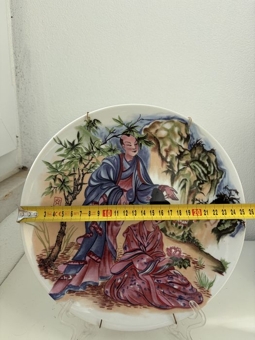 Prato decorativo em porcelana chinesa representando figuras.