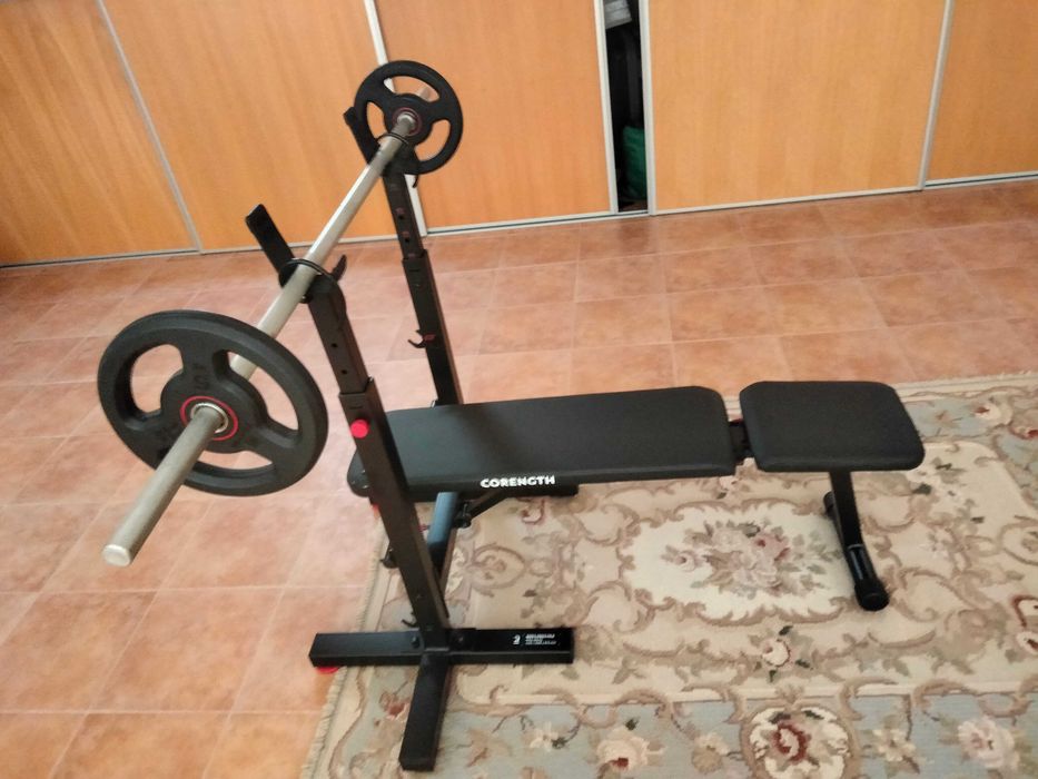 Banco de musculação com barra com dois pesos de 5 kg cada.
