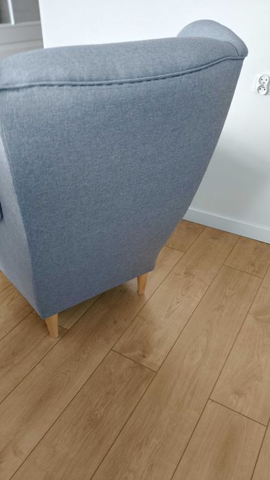 Fotel w stylu skandynawskim uszak używany w kolorze popielatym.
