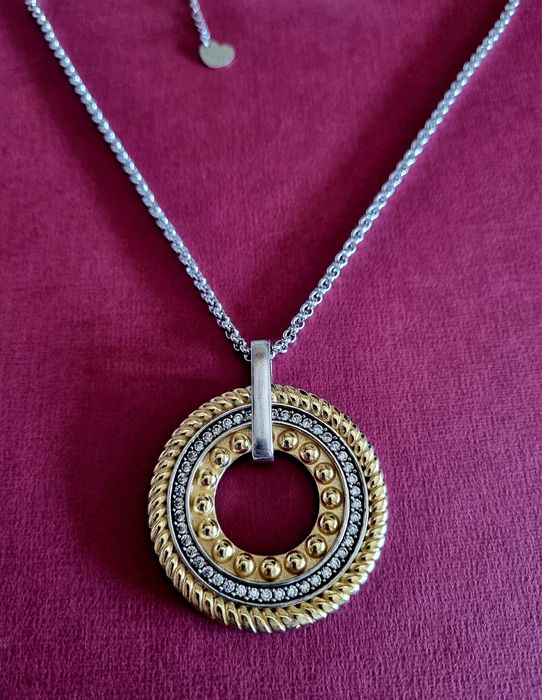 Colar prateado, em aço, com pingente bicolor. Tem extensor