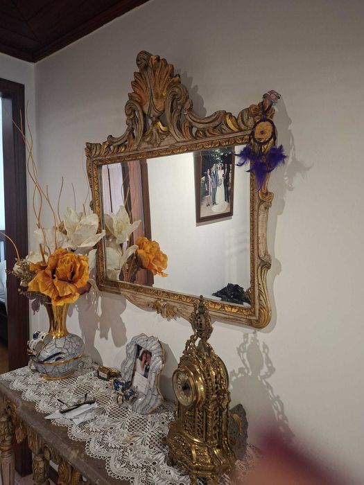 Conjunto decorativo composto por espelho de parede com moldura trabalhada e mesa de entrada com detalhes ornamentais