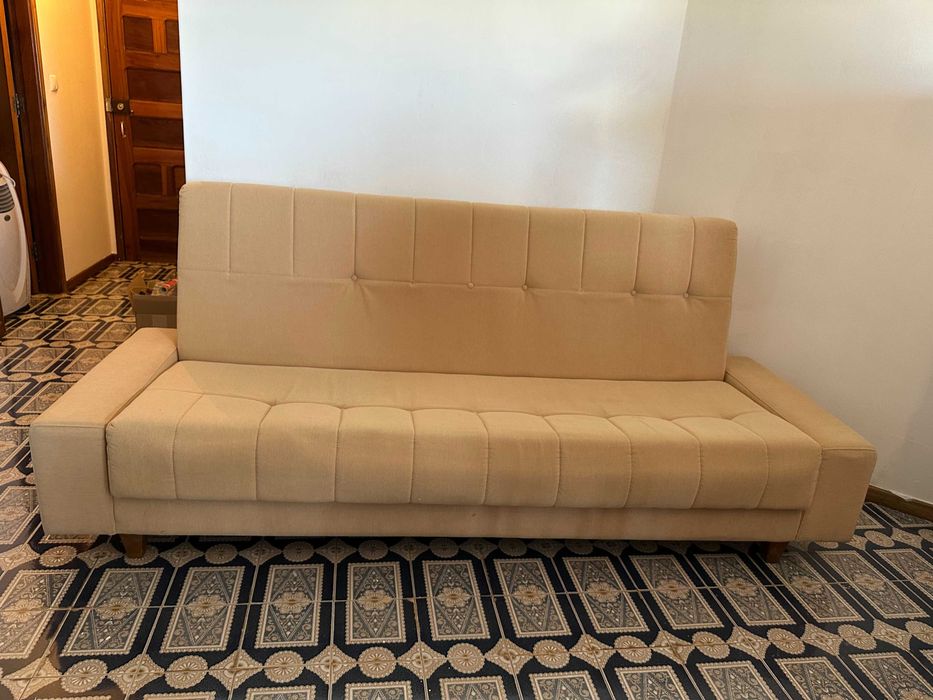Sofá-cama bege em bom estado.