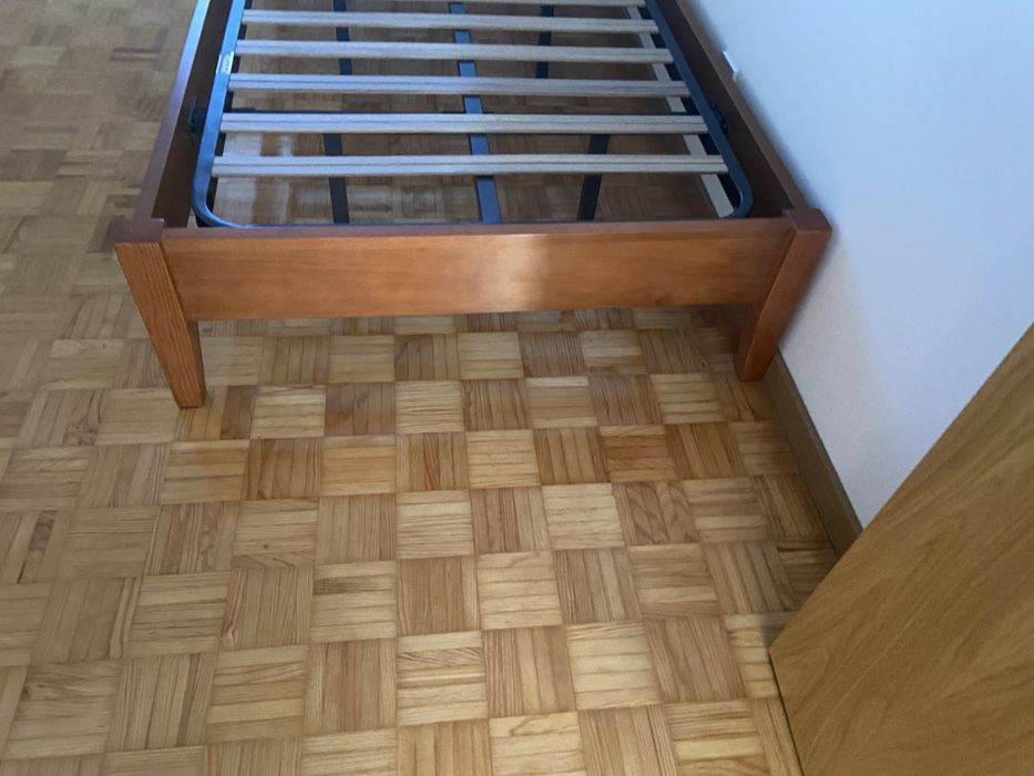 Cama individual de madeira macica e uma mesa de cabeceira