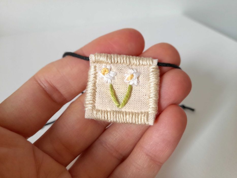 Pulseira bordada à mão com pingente de margarida branca