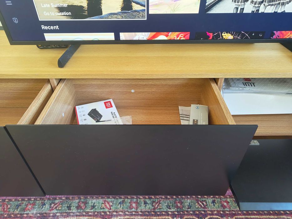 Móvel de TV preto com tampo em madeira
