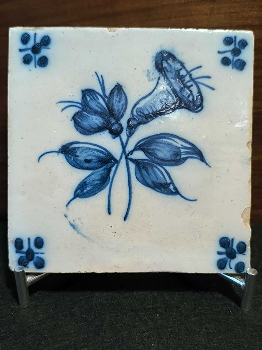 Azulejo antigo, em tons de azul, motivo plantas. Alguns sinais de uso