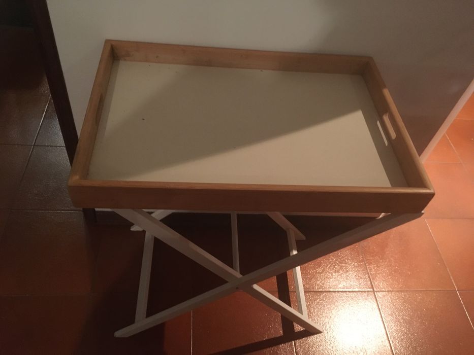 Mesa de apoio que assenta numas pernas de madeira dobráveis.