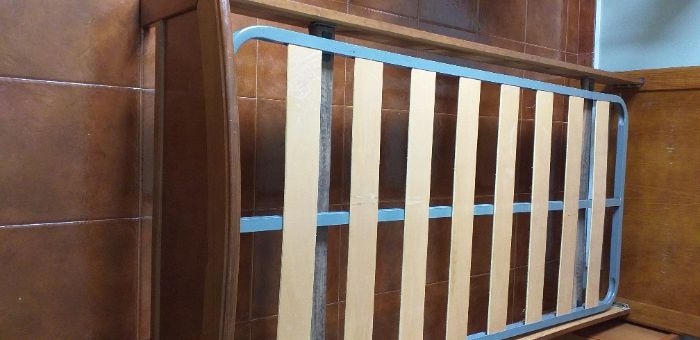 Cama de solteiro com estrado e mesa de cabeceira.