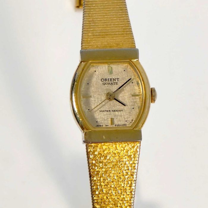 Relógio de pulso de senhora, Orient, caixa em metal dourado, bracelete em malha de metálica integrada em dourado. Movimento a quartz a funcionar