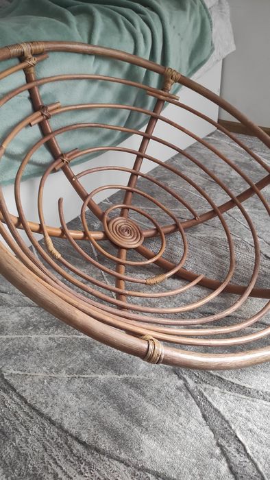 Duży fotel wiklinowy z poduszką.