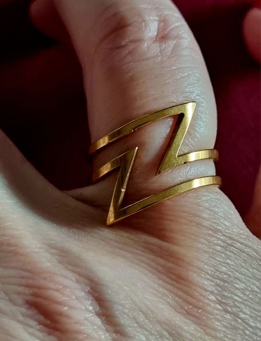 Anel dourado, em aço, em ziguezague. T18