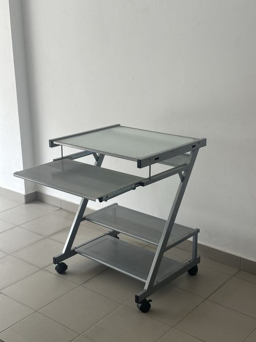 Secretária de computador compacta em metal e vidro.