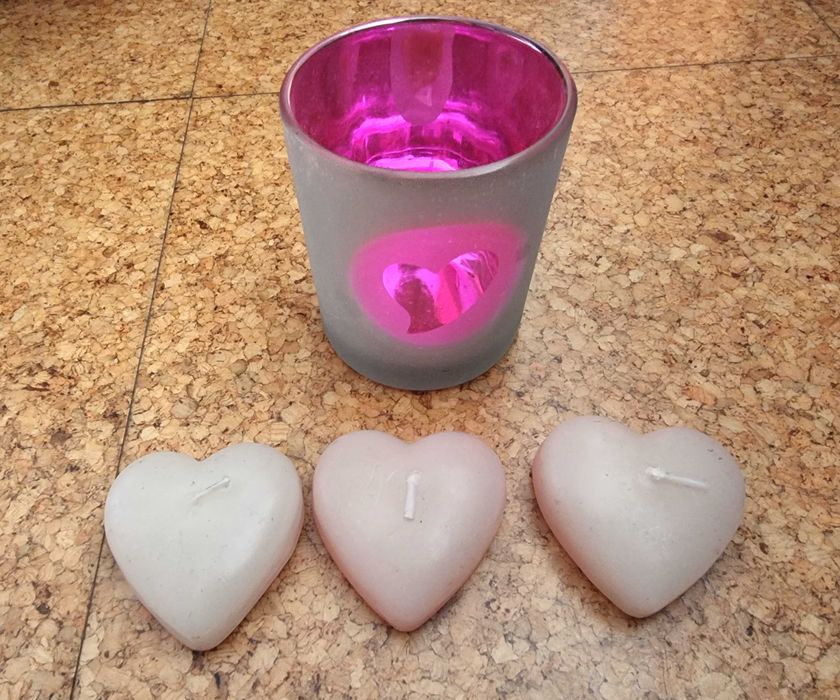 Copo em tons de rosa com três velas em formato de coração