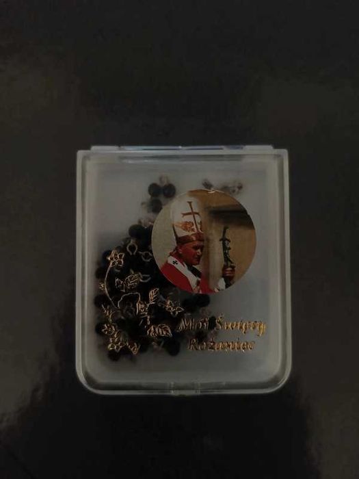 Różaniec komunijny z czarnymi perłami i pudełkiem z Janem Pawłem II.