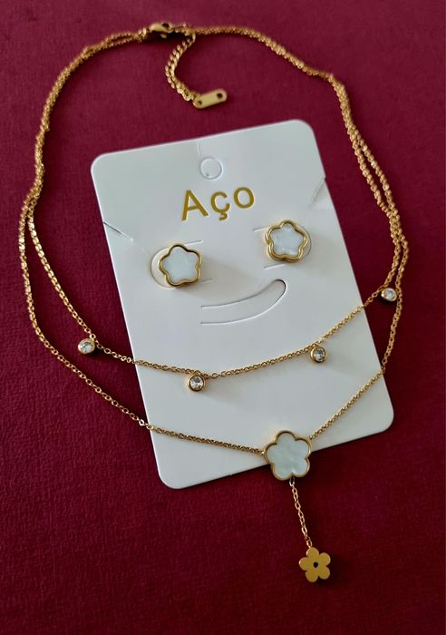 Conjunto dourado (colar duplo e brincos), em aço, com flores brancas em madrepérola.
