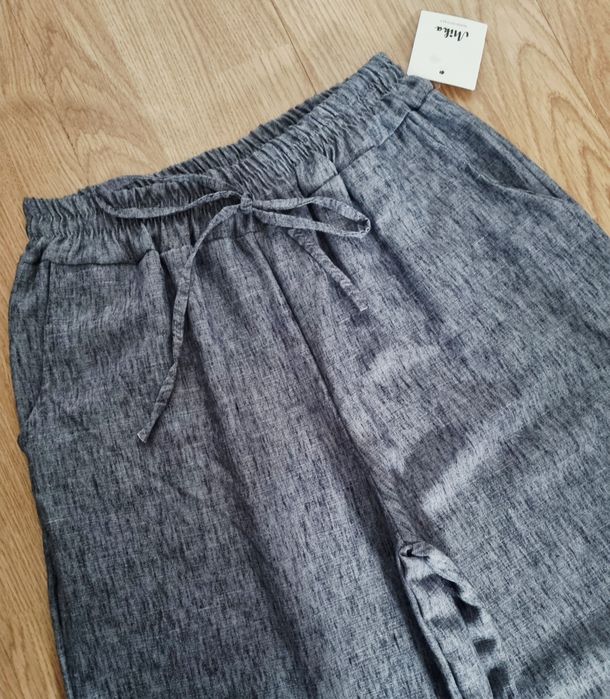 Calças pantalonas, em tons de cinza. Elástico na cinta e bolsos. TU
