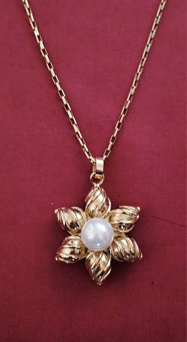 Colar dourado, em aço, flor com pérola. Tem extensor