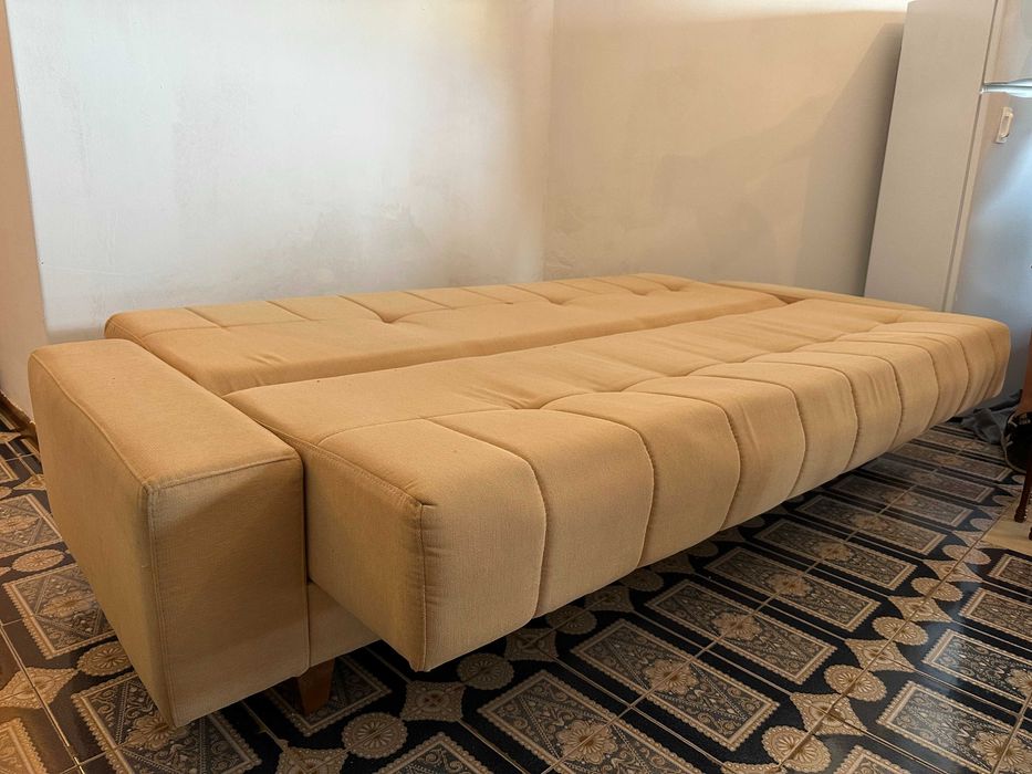 Sofá-cama bege em bom estado.