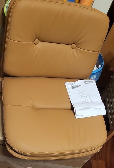 Banco de bar Cozyman possui estofado em pele sintética castanha com um design de assento duplo.