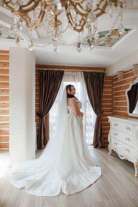 Весільна сукня білого кольору оздоблена квітами з розрізом