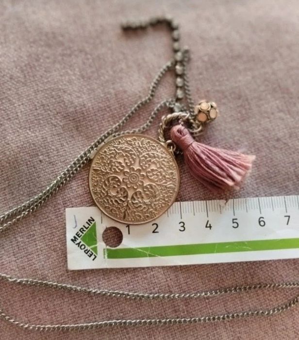 Colar com medalhão floral e borla rosa.