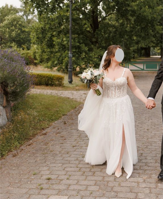 Suknia ślubna z gorsetową górą oraz kwiatowymi dekoracjami.