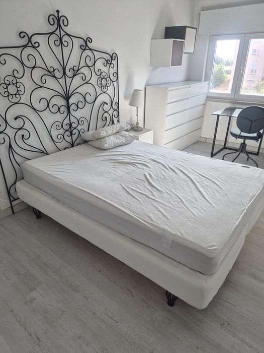Cama com cabeceira em ferro lacado preto.