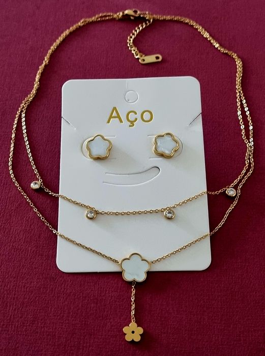 Conjunto dourado (colar duplo e brincos), em aço, com flores brancas em madrepérola.