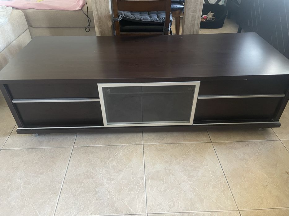 Brazowa szafka pod tv z szufladami i szklana czescia.