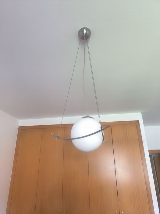 candeeiro suspenso com globo de vidro opalino e estrutura metálica curva, num estilo moderno