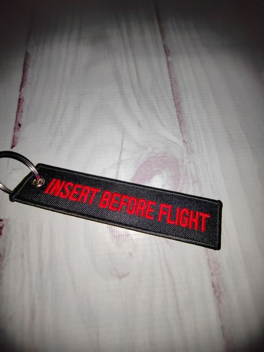 Czarny haft z czerwonym napisem Insert before flight