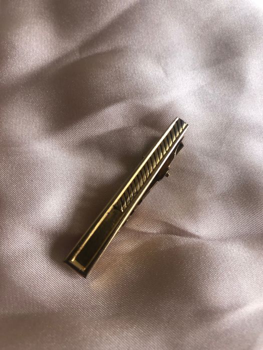 Peça dourada para segurar gravata a camisa
