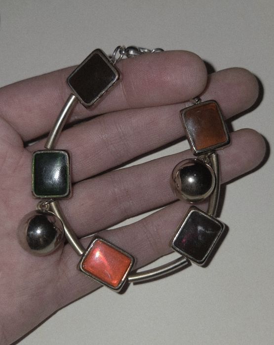 Metalowa bransoletka z geometrycznymi, emaliowanymi elementami.