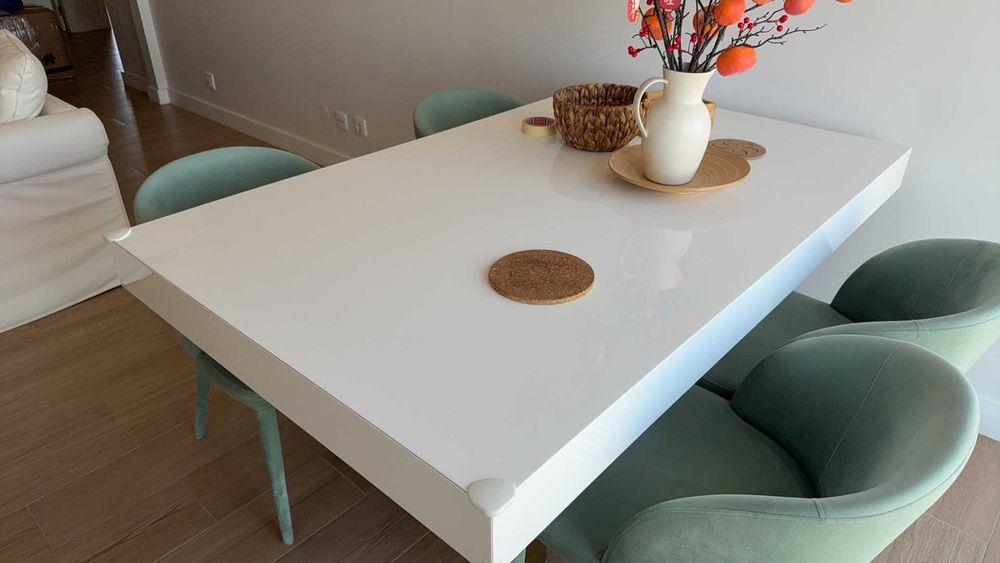Mesa de jantar branca com acabamento em esmalte cozido e quatro cadeiras em tecido