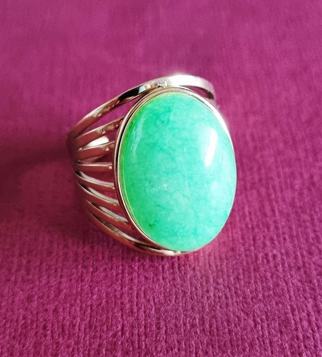 Anel dourado, em aço, com pedra oval verde claro. 18/ajustável