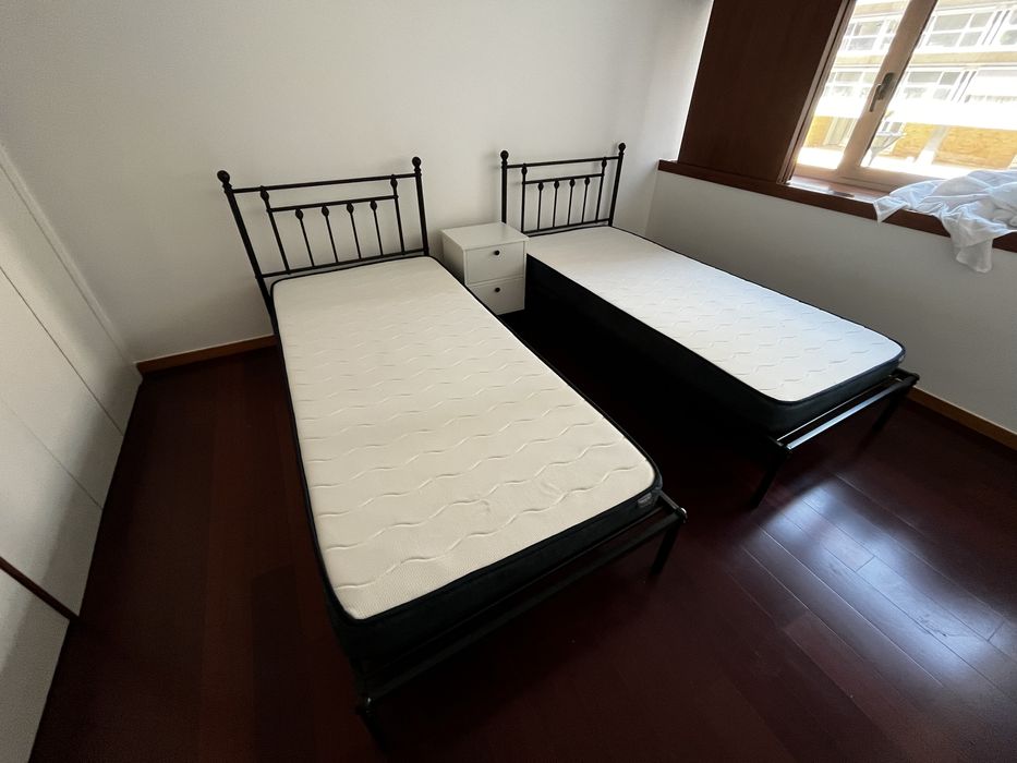 Duas camas em aço preto fosco, com colchões e capas de colchão