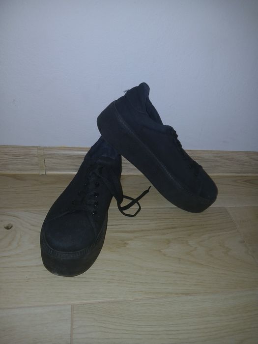 Czarne trampki na wysokiej podeszwie.