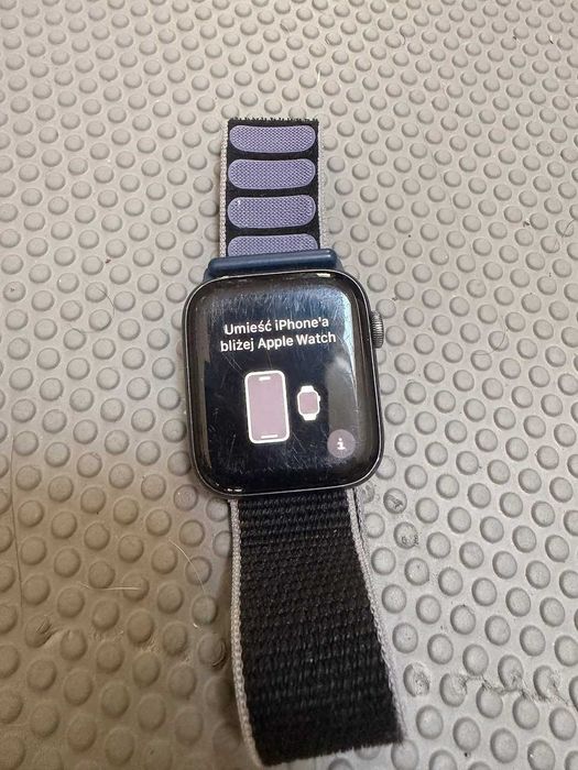 Sprawny Apple Watch w ciemnej obudowie z nylonowym paskiem i oryginalną magnetyczną ładowarką – gotowy do sparowania z nowym iPhone'em.