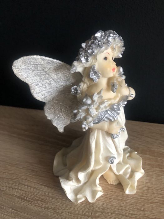 Figurka z żywicy Aniołek z różą i koszem kwiatów w ręku.