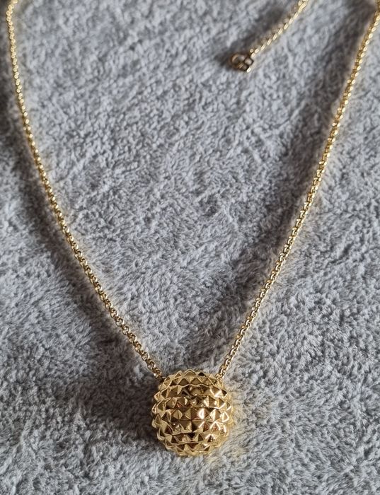 Colar dourado, em aço, com meia bola toda trabalhada. Tem extensor