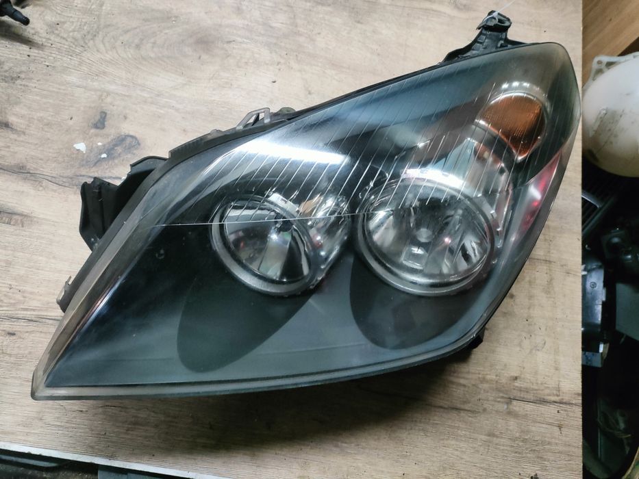 Opel Astra H III Reflektor lampa lewa uszkodzony zaczep