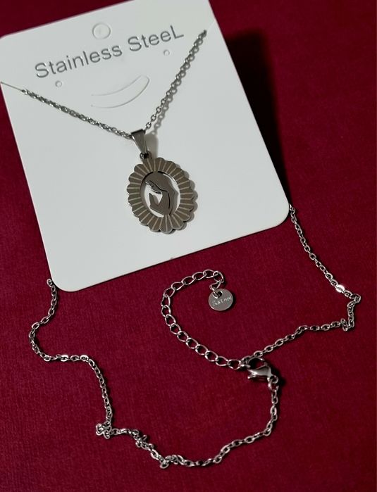 Colar prateado, em aço, com pingente da Nossa Senhora. Tem extensor